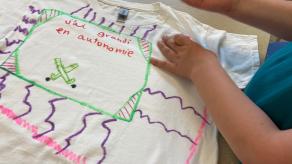 Une élève décore un chandail blanc des mots « j'ai grandi en autonomie ». Crédit photo @ Yves Amyot.