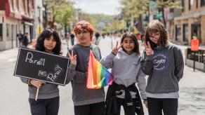 Quatre élèves posent devant la caméra, et tiennent un drapeau LGBTQ et une pancarte sur laquelle il est écrit "Pareil pas pareil"